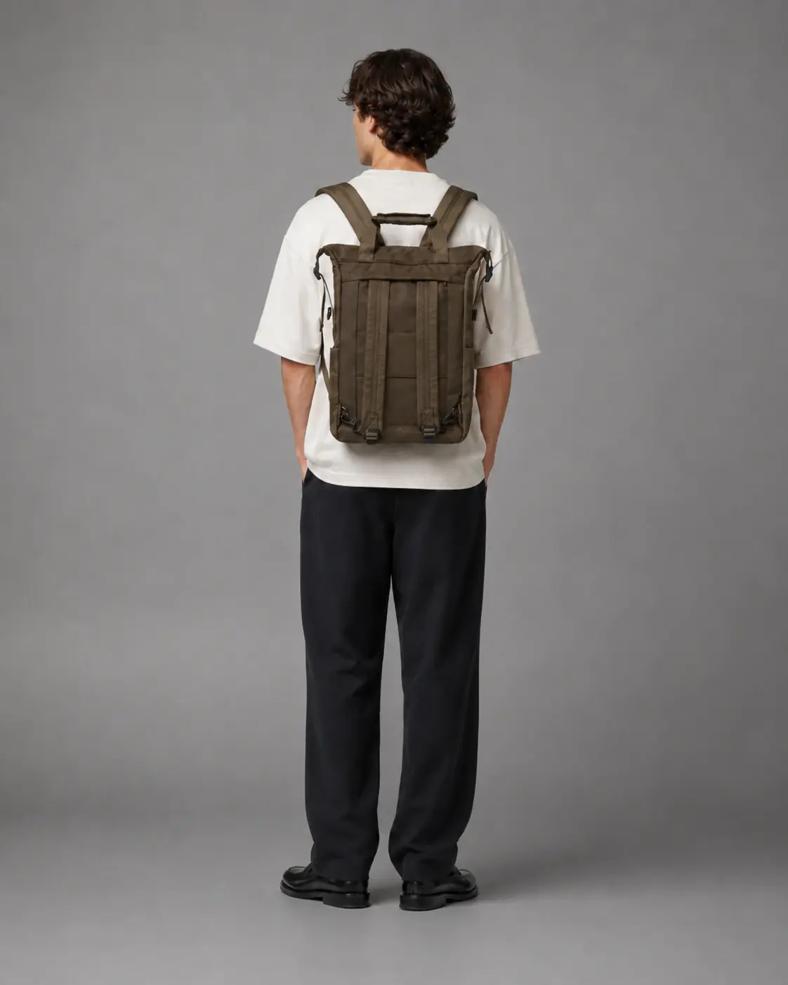 Model set bagfra med Nova Atelier Arven utility rygsæk i olivengrøn, hvid T-shirt og sorte bukser