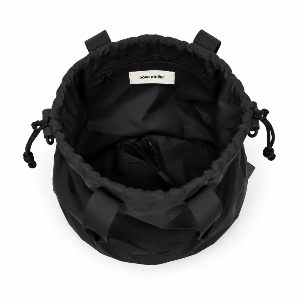 Nova Atelier Nivaro cinch pack i deep black set oppefra med åben snørelukning, indvendigt rum og sorte detaljer